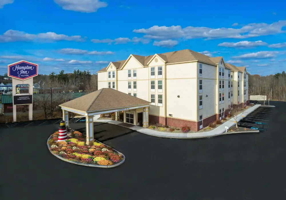 & Suites by Hilton in Charlotte, is a building with windows, surrounded by plants with flowers, a group of trees